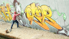 Wide viewof street artist painting colorful graffiti on generic wall   Modern art concept with urban guy performing and preparing live murale with multi color aerosol spray   Retro vintage filter